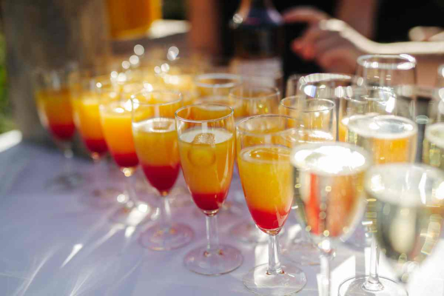  Invitados de boda disfrutando de un cóctel al atardecer en un beach club elegante de Ibiza