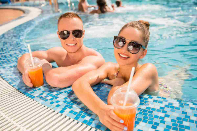 Pareja disfrutando de un day pass en la piscina de un hotel de lujo en Ibiza con vistas al mar Mediterráneo